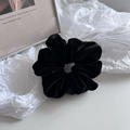 Detailed view of a thick black velvet scrunchie with rich folds on a minimalist background - Black