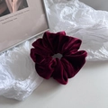 Detail of high-quality burgundy velvet scrunchie with lustrous texture and elastic band - Red