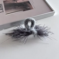 Close-up of grey knitted hair claw clip with ostrich feathers on a leather surface - 13cm / Gray