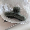 Close-up of a large dark green plush shark hair claw clip on a minimalist magazine - Green
