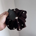 Detalle de coletero de terciopelo marrón oscuro con perlas elegantes y acabado de lujo - Marrón