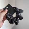 Dettaglio di un elastico in velluto grigio scuro con perle bianche e cartellino - Grigio