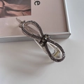 Detail view of transparent bow hair claw clip with dark grey rhinestones and gold spring - Gray