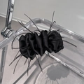 Detail view of black feather hair clip with pleated satin texture on display stand - Black
