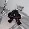Detail of premium velvet bow hair tie on a minimalist chair showing luxury texture - Brown