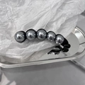 Dettaglio delle perle grigie su un fermaglio a banana in resina nera metallizzata - Grigio
