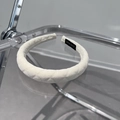 Primer plano detallado de la diadema acolchada blanca con una etiqueta negra hecha a mano - Beige