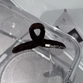 Close-up of brown suede hair claw clip with sparkling rhinestones and gold logo detail - Brown
