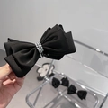 Dettaglio dell'elegante fiocco per capelli in raso nero con tre file di perline argentate - Nero
