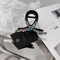 Dettaglio di un elegante fermaglio nero con strass colorati e cartellino premium - Multicolore