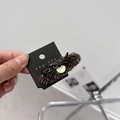Close-up of brown knit hair claw with black bow and gold pendant detail - Small Oval Coffee