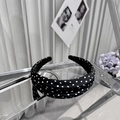 Detail of a wide black polka dot padded headband on a reflective stand with vintage vibe - Headband
