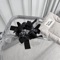 Detail of plaid scrunchie with black satin bows on minimalist acrylic background - Black