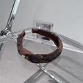 Dettaglio di un cerchietto floreale intrecciato marrone scuro con accenti dorati su acrilico - Catena Ritorta