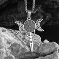 Macro shot of stainless steel Triple Moon Hecate Wheel pendant on grey stone background - Steel