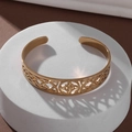 Detailed top view of gold-plated stainless steel open bangle with intricate Celtic knot patterns - Gold