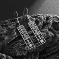 Detail of Eye of Horus cutout stainless steel earrings hanging on a gray textured rock - Eye of Horus Style (21766) / Silver