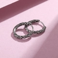 Close-up of vintage oxidized silver hoop earrings with bohemian engraved patterns - Antique Silver