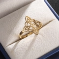 Macro shot of gold witch's knot ring showcased in a blue velvet gift box - Gold