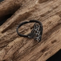 Macro shot of black stainless steel Celtic knot ring on natural wood surface - Black