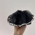 Dettaglio di un grande elastico in organza nera con eleganti perle bianche e pieghe in rete - Nero