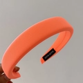 Detailed macro view of the bright orange sponge headband with a hand made woven label - Orange