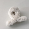 Gros plan d'une pince à cheveux en peluche beige montrant la texture douce et le ressort - Blanc
