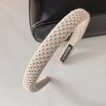 Detailaufnahme des beigen Strickstirnbands mit Handmade-Etikett auf einer Tasche - Aprikosengrau