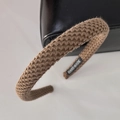 Detailansicht eines braunen Strick-Haarreifens mit gerippter Textur und Hand-Made-Etikett - Hellkaffee