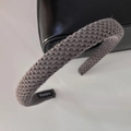 Makroaufnahme des grauen Strickstirnbands mit Textur und handgefertigtem Stoffetikett - Grau