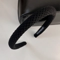 Detail of black knitted headband featuring a handmade label and textured yarn weave - Black