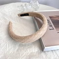 Dettaglio fascia larga intrecciata beige con etichetta HAND MADE su sfondo strutturato - Stile Intrecciato in Tweed / Cachi chiaro