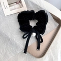 Dettaglio macro dello scrunchie in velluto nero con perle e fiocco elegante - Nero