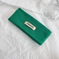 Dettaglio della fascia in maglia verde con etichetta 'FASHION' crema su sfondo bianco - Verde