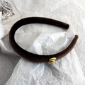 Primer plano de una diadema de terciopelo marrón oscuro con un detalle dorado de letra S - Estilo Letra S / Marrón