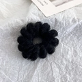 Dettaglio di un morbido elastico in lana nera con design ondulato su sfondo di carta bianca - Nero