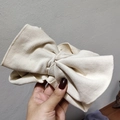 Close-up of cream knit headband showing ribbed texture and large bow detail - Beige