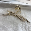 Detailaufnahme einer goldenen Schleifen-Haarklammer mit Strasssteinen und weißer Perle - Streamer Schleife Stil
