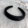 Close-up of a thick black satin headband with a high crown design on white art paper - Black