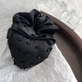 Dettaglio di elastico in raso nero con fiocco a cuore di perline su vassoio di legno - Nero