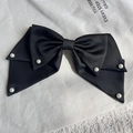 Close-up of black satin bow hair clip with elegant pearls on textured white background - Black