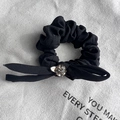 Detail of black chiffon bow hair tie featuring a large sparkling central rhinestone - Black