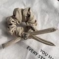 Detail of beige quilted bow scrunchie with Czech rhinestones and metal brand tag - Khaki