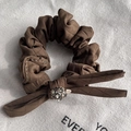Detail of a brown quilted fabric hair scrunchie with a bow and faceted grey crystal bead - Brown
