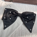 Nahaufnahme einer eleganten schwarzen Satin-Schleife mit Perlen auf weichem Hintergrund - 3 Perlen Stil