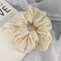 Detail eines beigen Haargummis mit gestreifter Plissee-Textur und feiner offener Kante - Beige