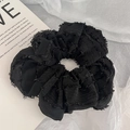 Detail eines schwarzen Scrunchie mit Fransenrand auf künstlerischem weißem Hintergrund - Schwarz