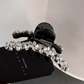 Detail view of a black shark hair clip with sparkling rhinestones on a display card - Small (6cm)