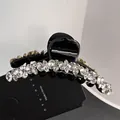 Detail of a large black claw clip adorned with sparkling rhinestones and a glossy finish - Medium