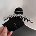 Detailed macro view of an elegant black hair claw clip with sparkling rhinestones decoration - Large